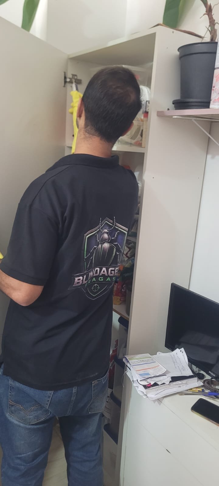 Técnico uniformizado da Blindagem Pragas durante atendimento em armário